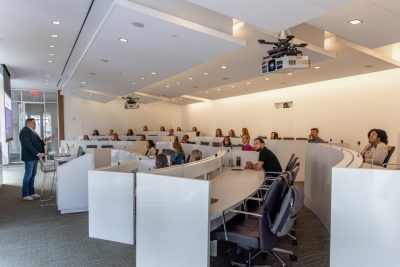 group of people listening to a speaker in a white room