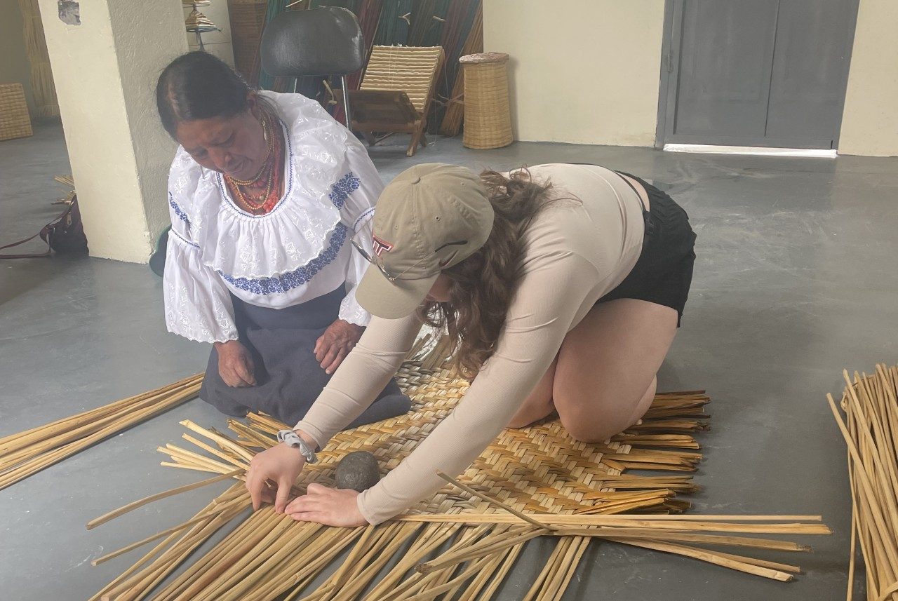 Morgan Harvey weaving reeds into a basket with the help of a local Otavolo woman. Photo by Matt Eick for Virginia Tech.
