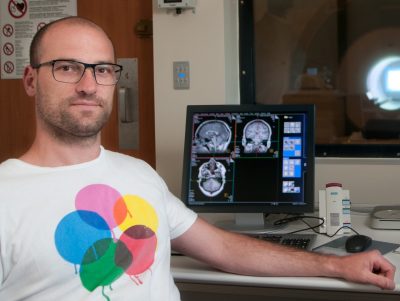 Ulrick Kirk in front of monitor showing brain scans