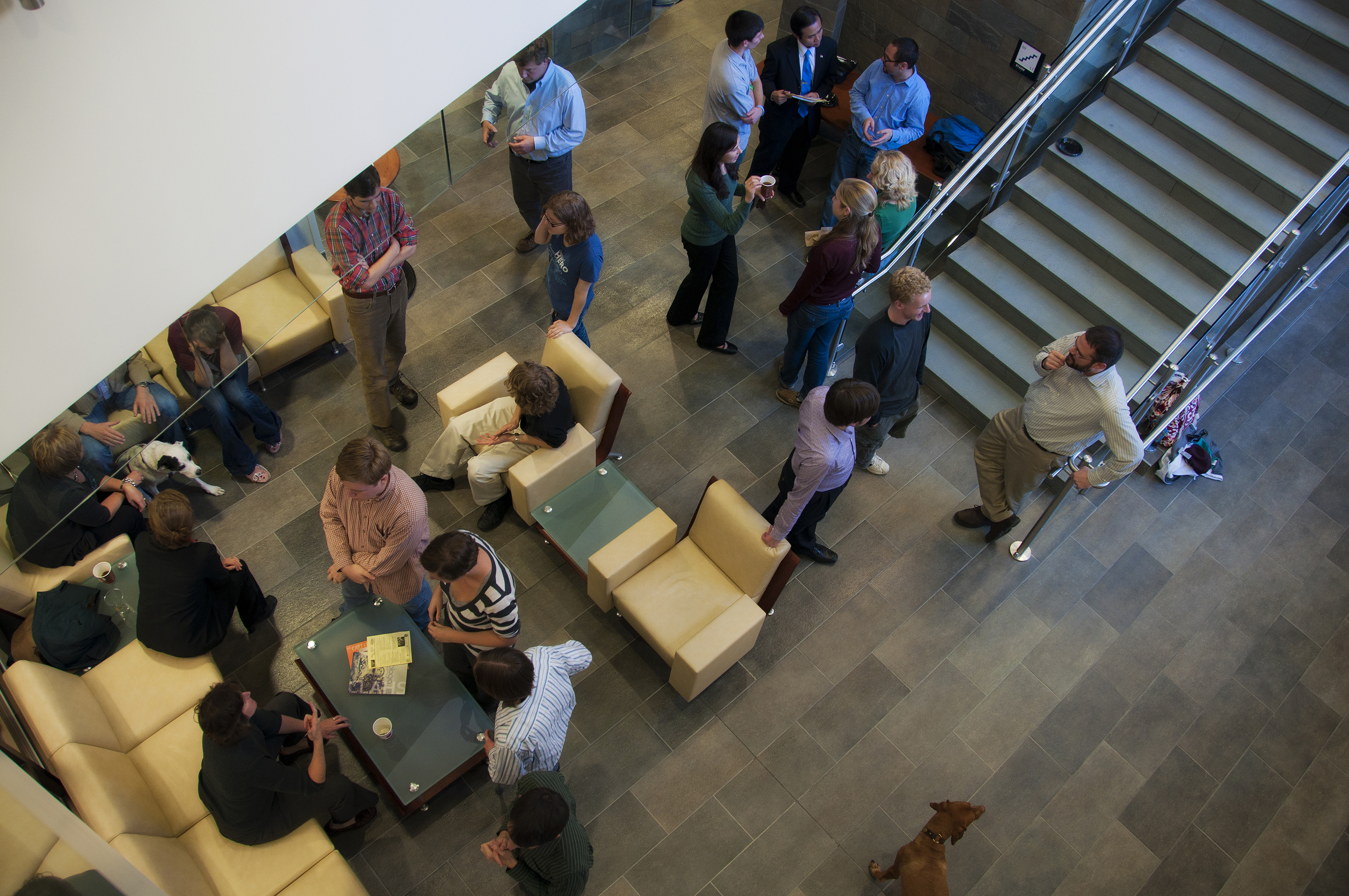 View looking down on a large group of students, faculty, and staff interacting in an open atrium area.