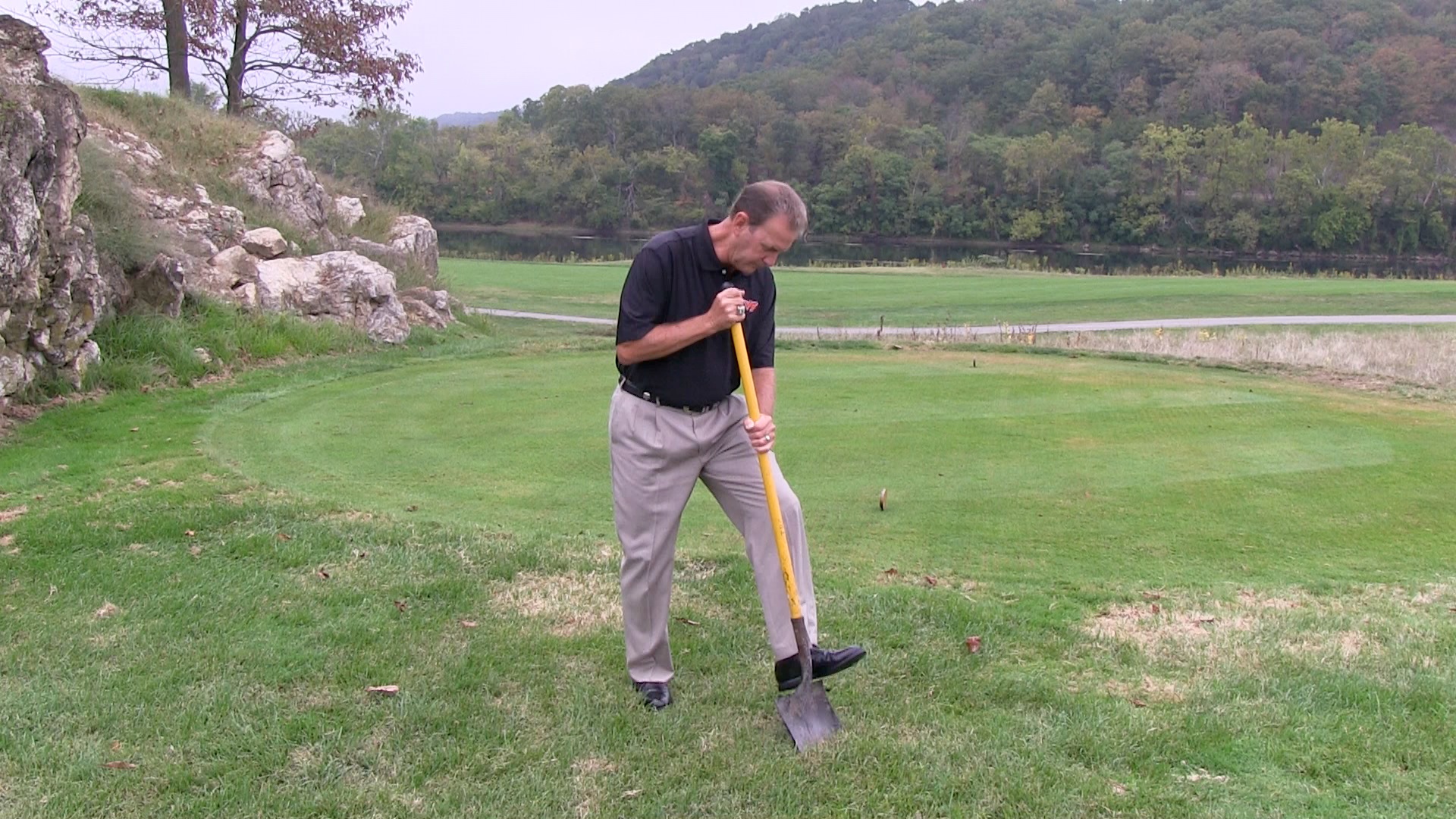The head golf coach at Virginia Tech, Jay Hardwick, uses a shovel to dig up some soil. He's checking to see whether there are any layyers of clippings and dead roots.
