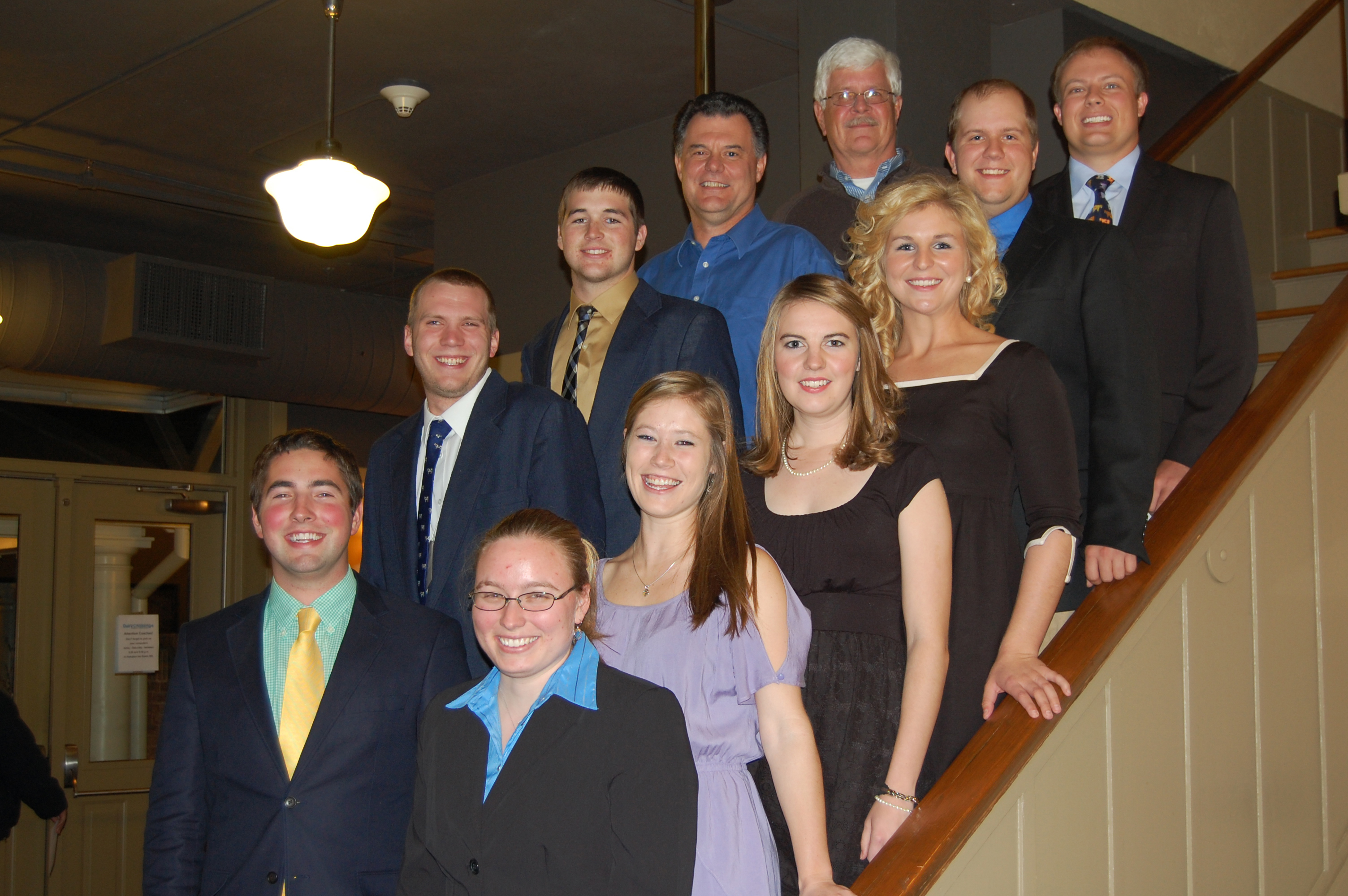 A group photo of nine students and two professors standing on a staircase. The students participated in the North American Intercollegiate Dairy Challenge.