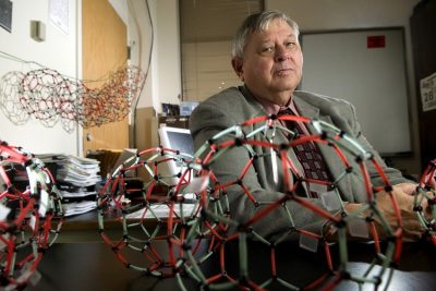 Harry Dorn behind his desk that is covered with colorful chemistry models.