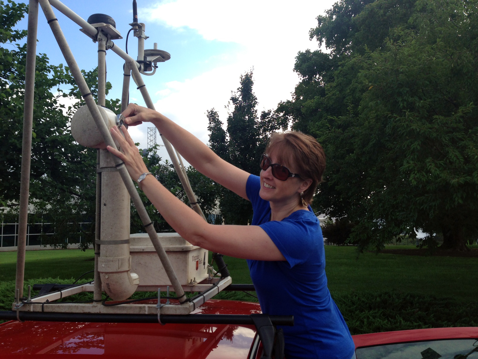 Tammy Parece adjusting equipment on top of a minivan.