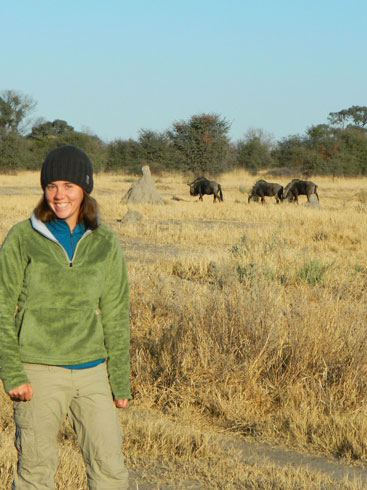 Lindsey Rich stands on the savannah with wildebeest in the background