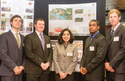 The five students on the second place team stand with their presentation board.