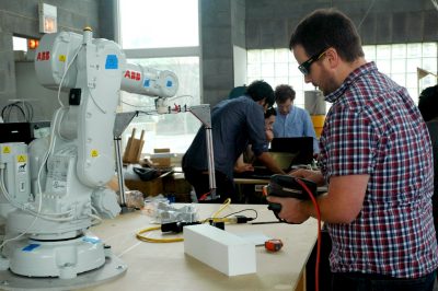 A summit participant works with a robot to create a small prototype. 