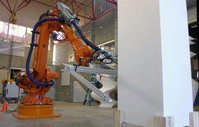 A large orange industrial robot slices through a white tower. 