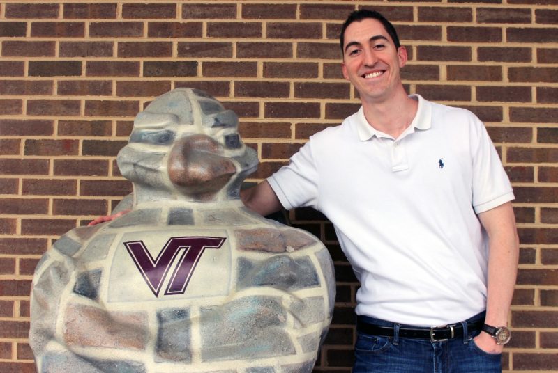 David Duckett stands with a statue of the HokieBird outside of his office.