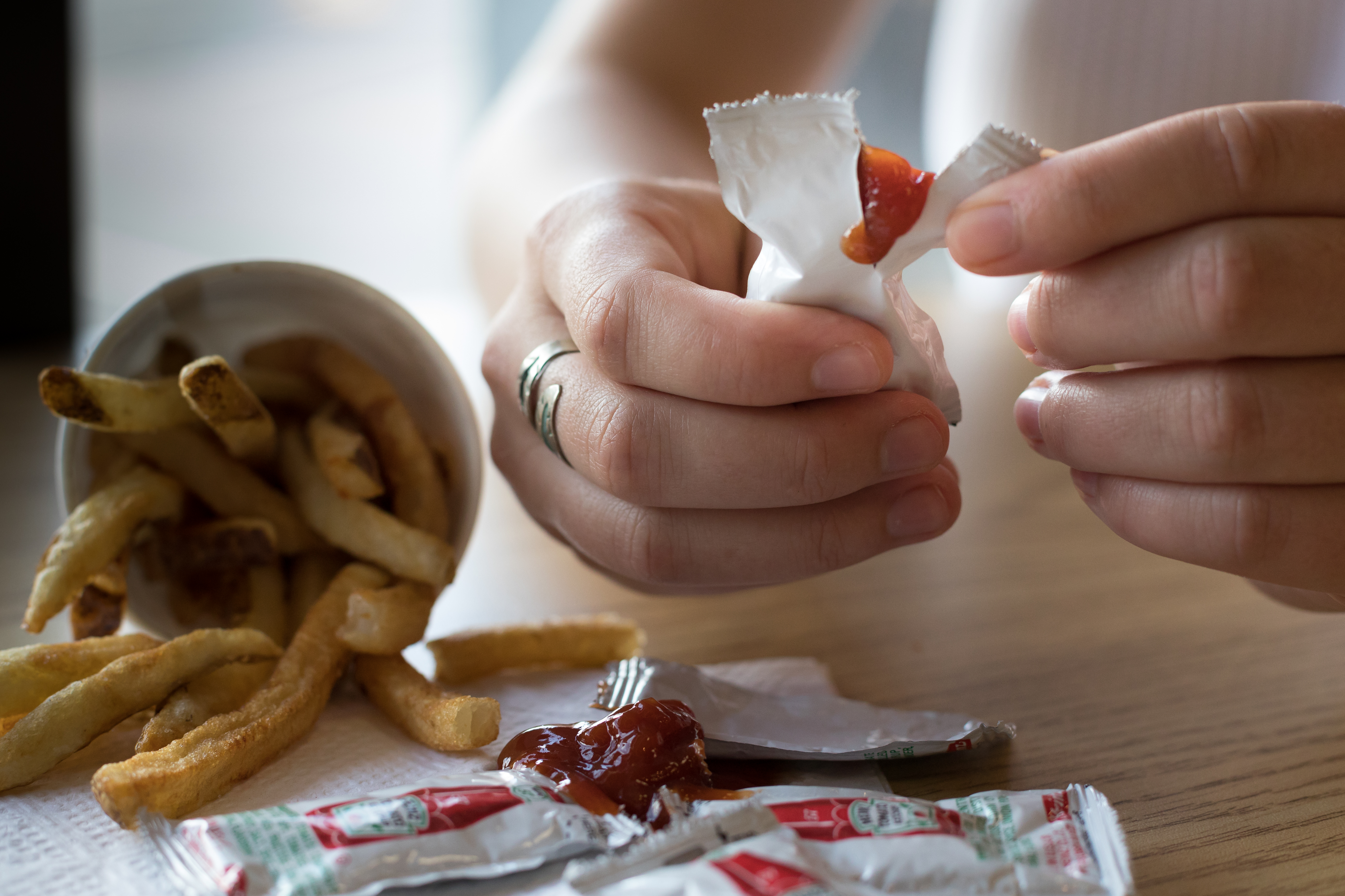 a person opening up a ketchup packet