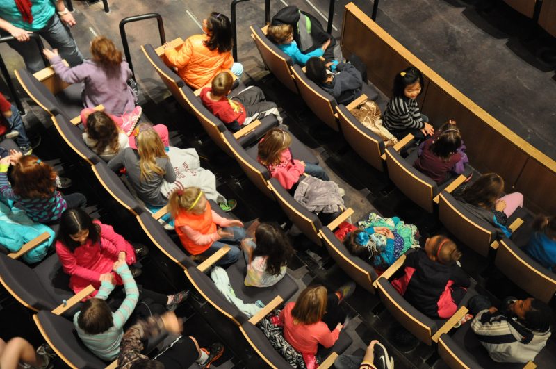 A group of students sit in their seats in the Moss Arts Center theatre.