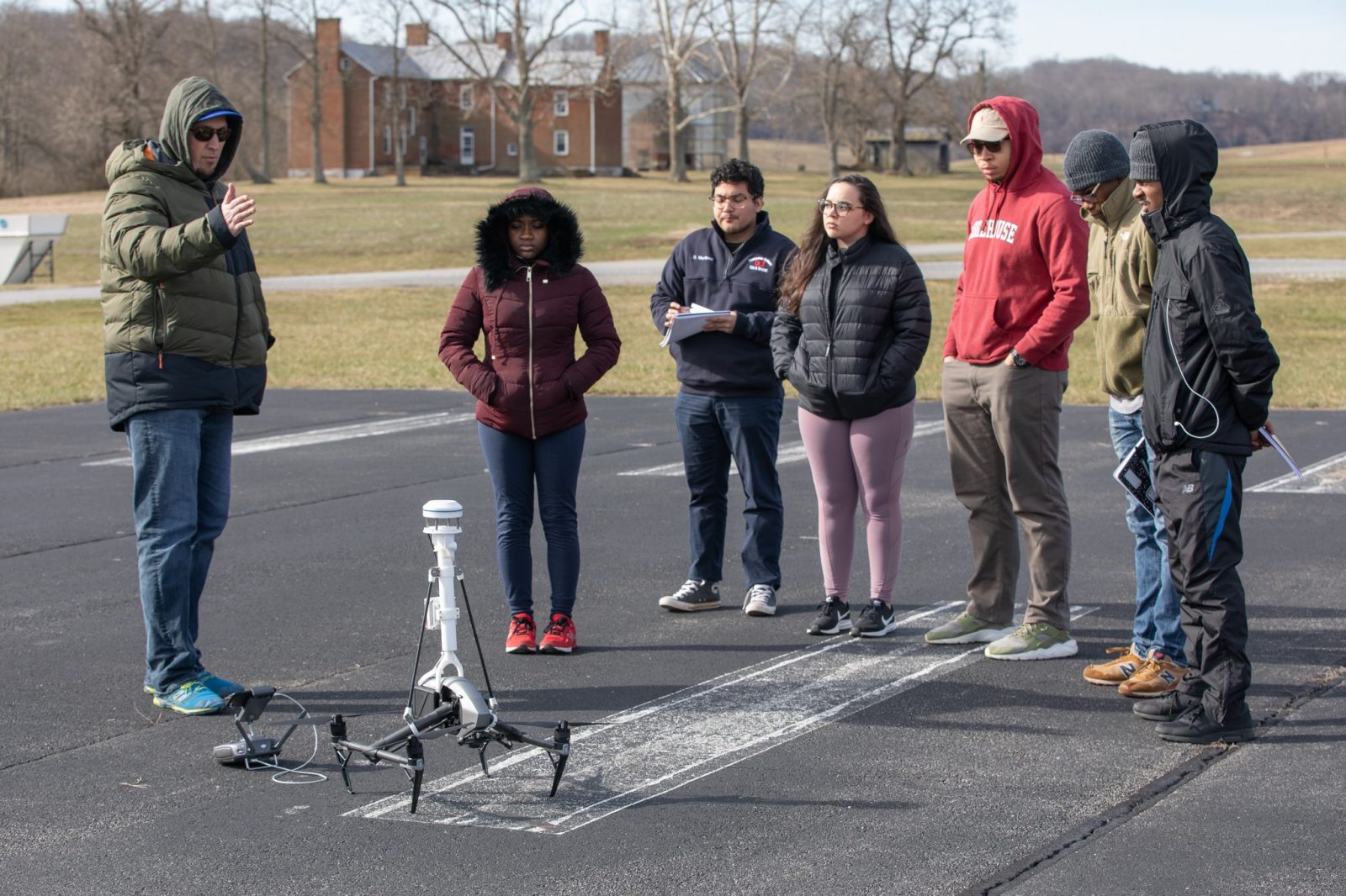 Undergraduates from Bennett, Morehouse, and Hampden Sydney stand on an airstrip at Virginia Tech’s Kentland Farm. They look at a drone as David Schmale prepares them for a data sciences mission to monitor wind  Courtesy of Peter Means.