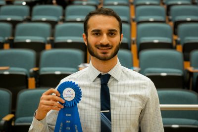 Man holding Letter of Distinction ribbon standing in front of empty auditorium.