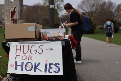A poster that says "Hugs for Hokies" is taped to the end of a table on the Drillfield