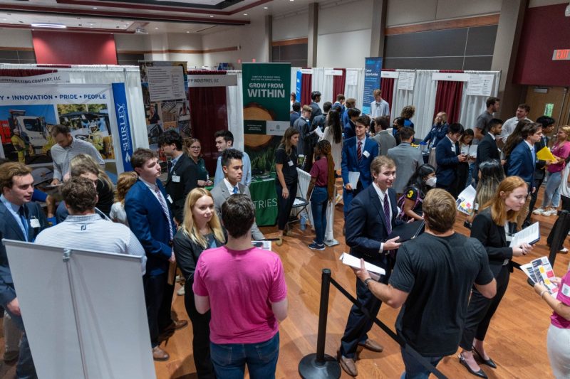 A crowd of students gather around employer booths set up in commonwealth ballroom.