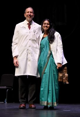 VTCSOM Dean Lee Learman poses on stage with first-year student Snigdha Nandipati after she receives her white coat. 