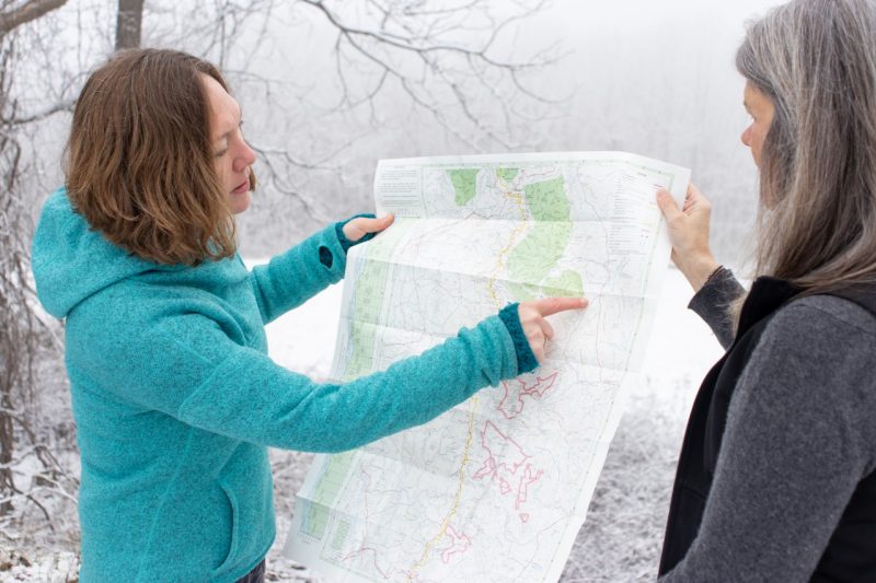 Emily Satterwhite (at left) points out areas of Appalachia on a map that she expects to highlight as part of a $3 million project to commemorate the region's neglected history. Satterwhite and Katy Powell (at right), both faculty in the College of Liberal Arts and Human Sciences, are leaders of the project. Photo by Mary Crawford for Virginia Tech.