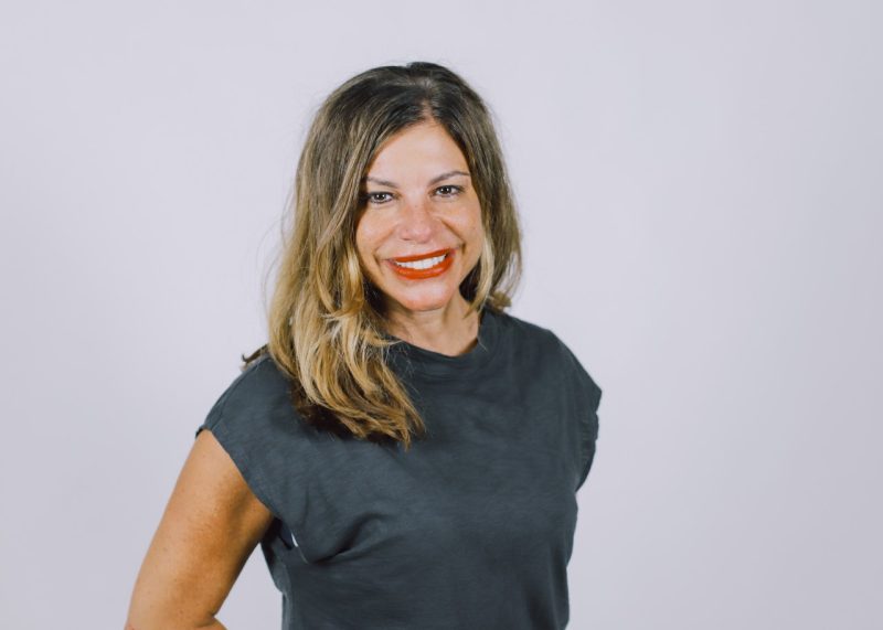 woman in front of a white background wearing a black shirt,