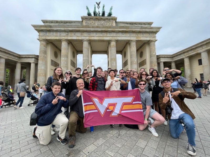Students stand in front of German landmark while holding the Virginia Tech flag