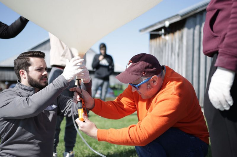 Kevin Sterne assists Ph.D. student Connor Segal with filling up a scientific weather balloon for an undergraduate experiment at the Kentland Experimental Aerial Systems Laboratory. 