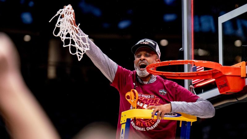 Coach Kenny Brooks holds the net cut down during a tournament win