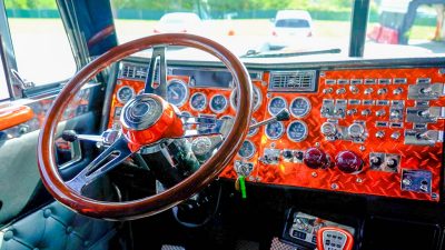 The steering wheel and custom orange dashboard inside of the VTTI 1995 Peterbilt truck