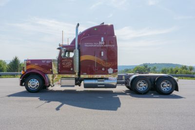 The passenger side of a maroon 1995 Peterbilt semi-truck with Virginia Tech colors and decals