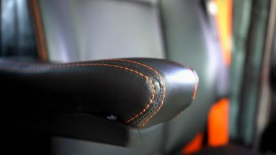 A black leather armrest with orange stitching.