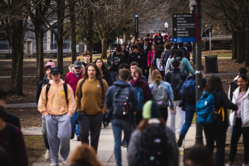 Dozens of people walk along a sidewalk on Virginia Tech's campus. 