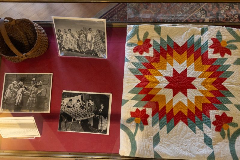 a picture of items in the exhibit including a quilt, pictures and a basket