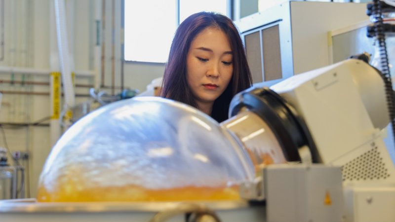 Woman in a research lab behind a maachine used to help make biodegradable bioplastics.