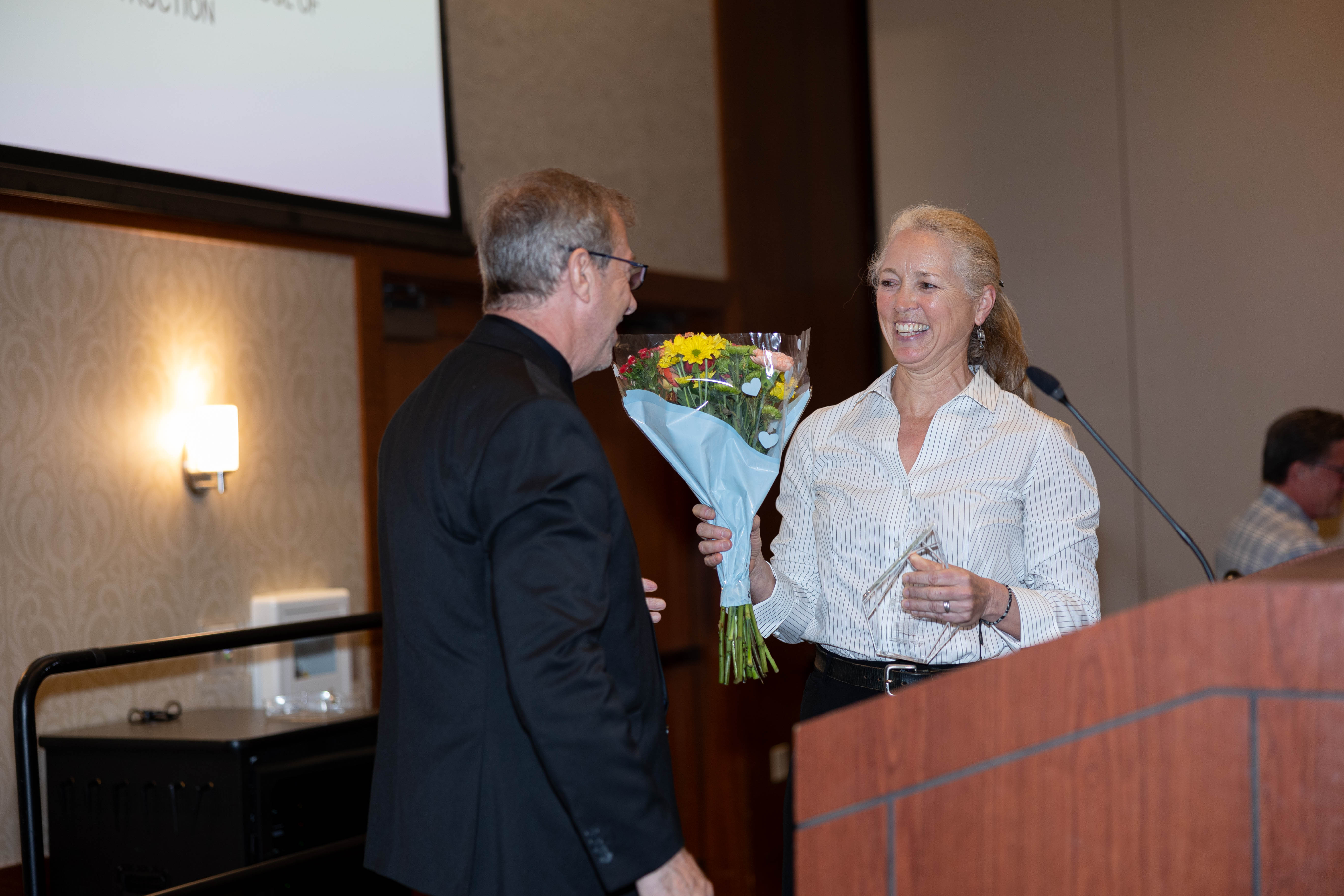 Brian Kleiner (at left) gives Kirsten Leckszas '88 flowers and her award. Photo by Will Drew for Virginia Tech.