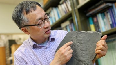 Shuhai Xiao holds up a fossil