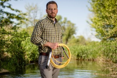 A person holding an instrument stands in a creek. 