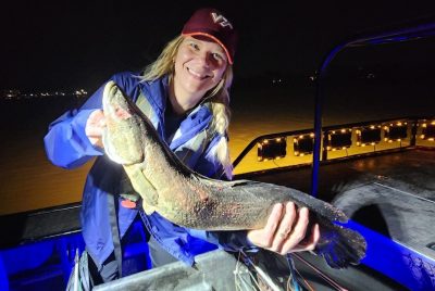 A person on a boat holds a large fish.