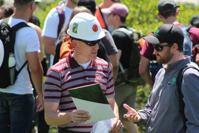 A person in a safety hardhat talks to another person. 