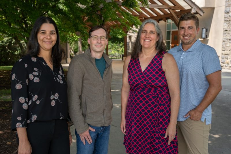 four people side by side standing outside