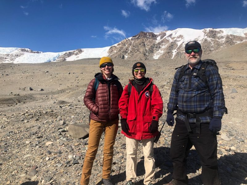 Three individuals stand in Taylor Valley, located in Antarctica.