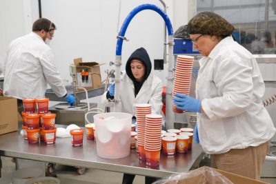 Homestead workers and Virginia Tech's Joell Eifert fill pint containers on the production line