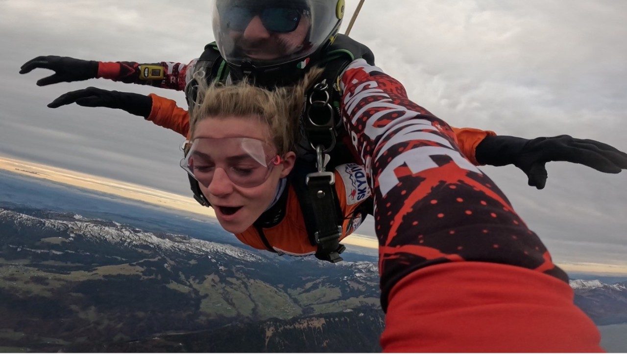 A female student skydives over Switzerland.