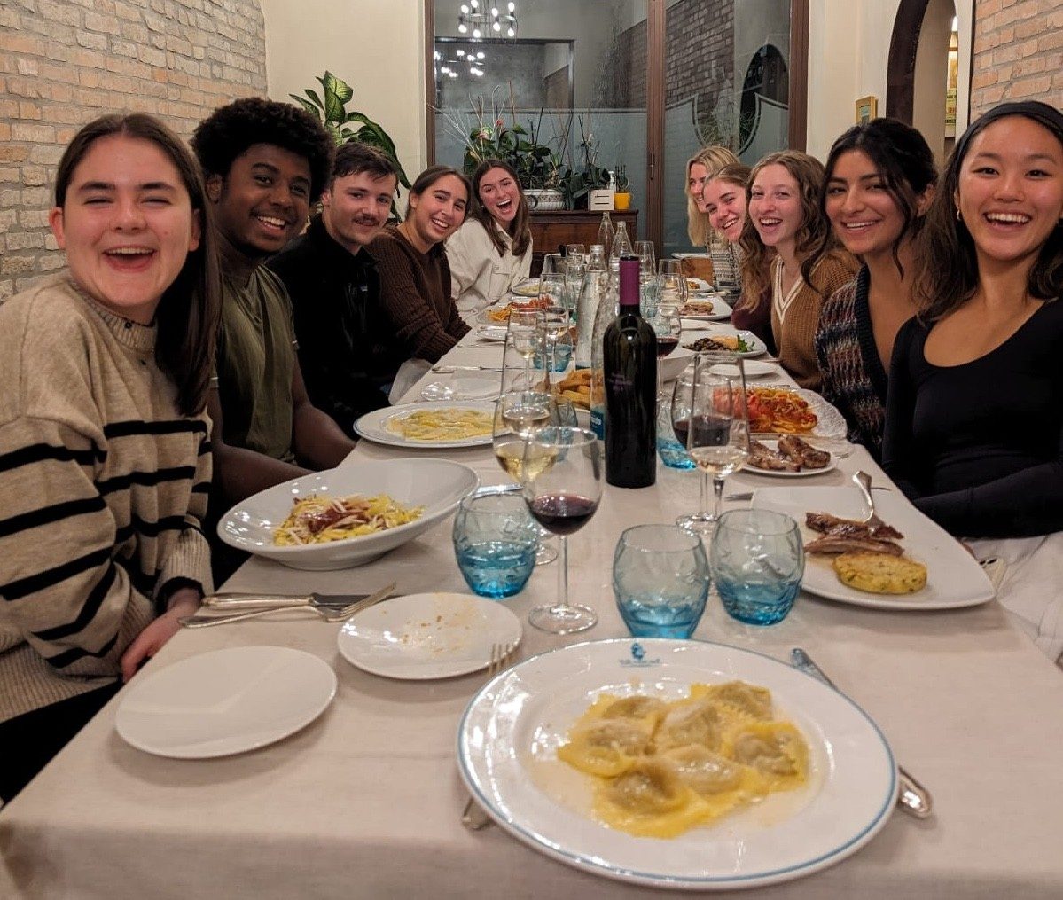 A group of students smiles, sitting at a dinner table.