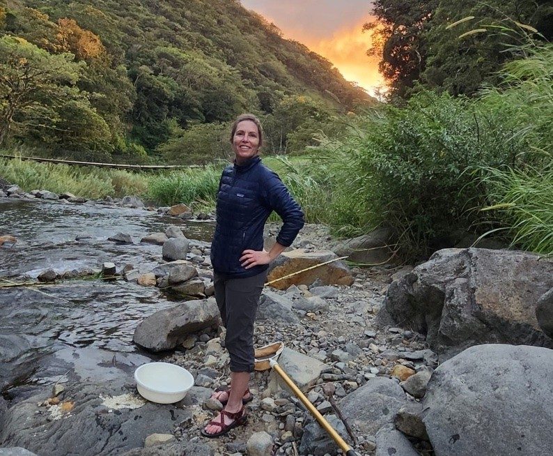 Sally Entrekin standing at a stream in the mountains.