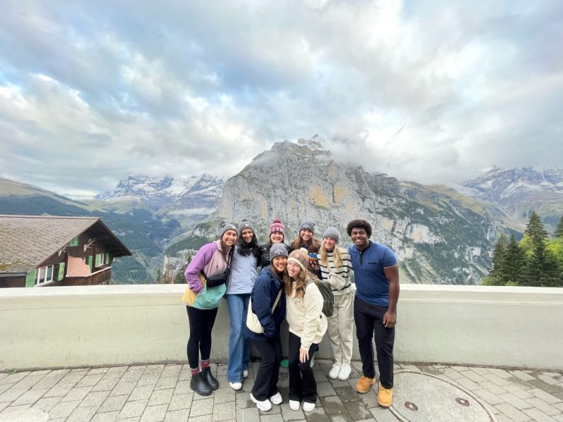 A group of students pose in front of a mountain.