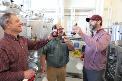 Herbert Bruce, Sean O'Keefe, and Brian Wiersema, the Virginia Tech food science faculty members who developed the recipe for the beer, hold bottles of Fightin' Hokies Lager in the on campus brewery.