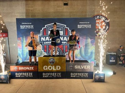 Three individuals stand on awards podium.