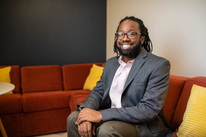 Man sits on couch and smiles.