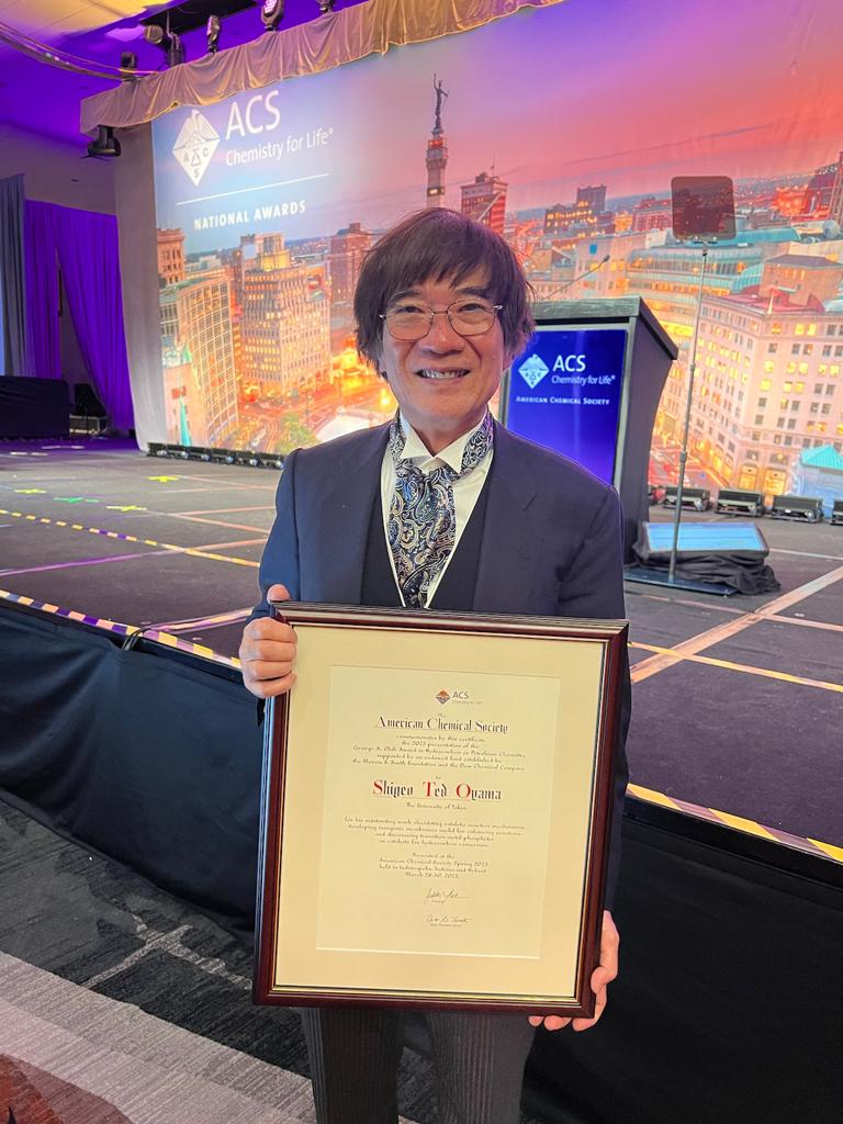 Award recipient holds framed award.