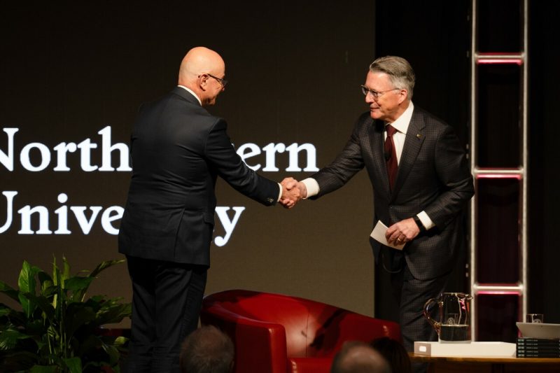 Two men shake hands on a stage