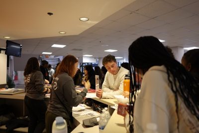 Students checking in. staff assist them from behind the counter