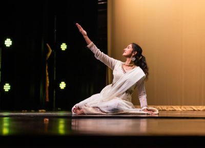 Female dancer in white sari performs on stage